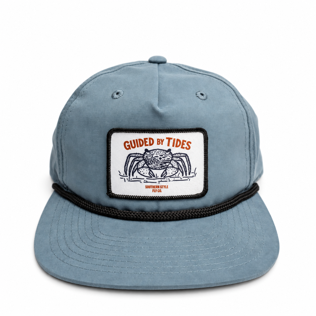 Front view of the slate-blue Mangrove Rope Hat with black rope and Guided by Tides crab patch.