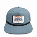 Front view of the slate-blue Mangrove Rope Hat with black rope and Guided by Tides crab patch.