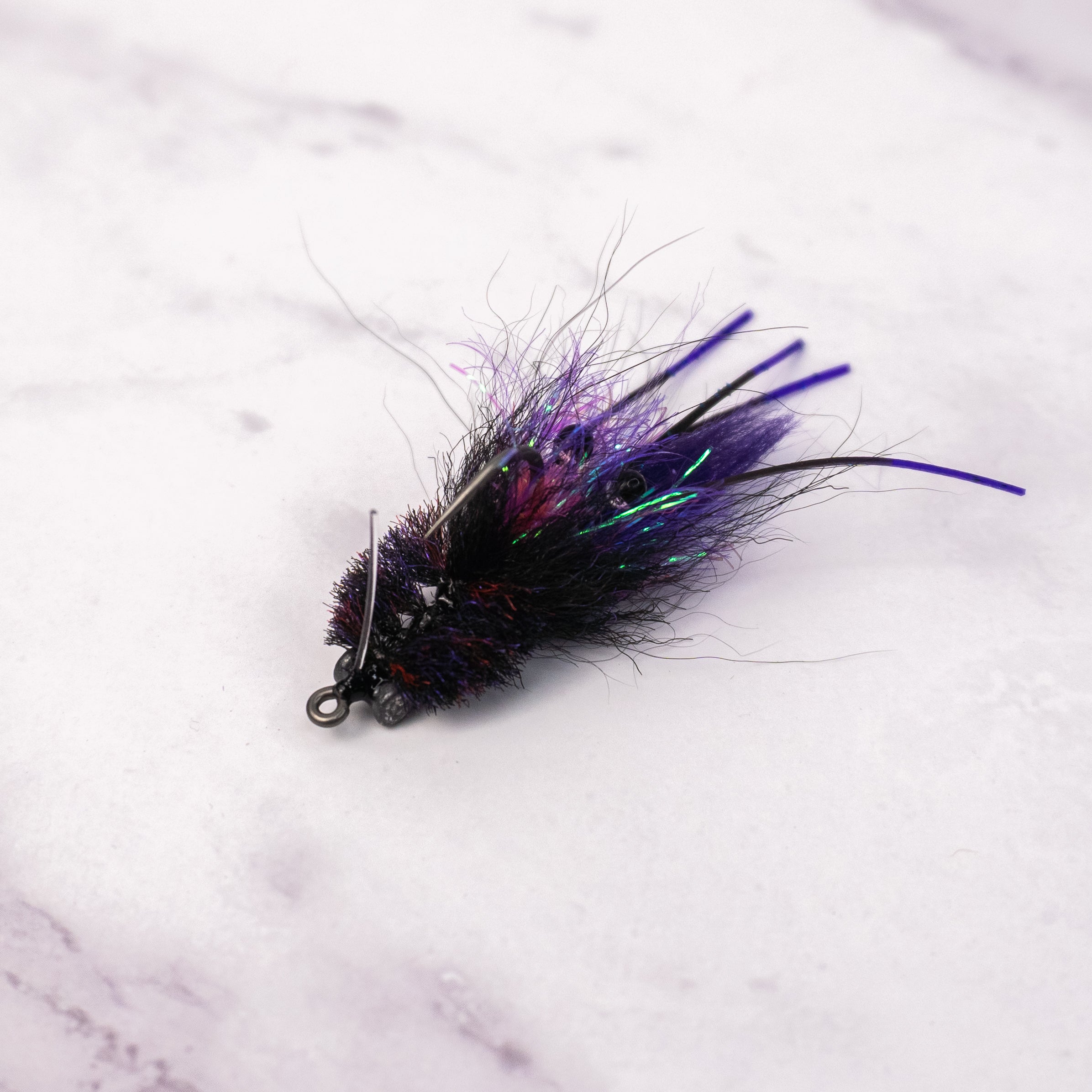 Black and purple Bandit Crab fly with flash, rubber legs, weighted eyes, and weed guard for low light redfish fishing