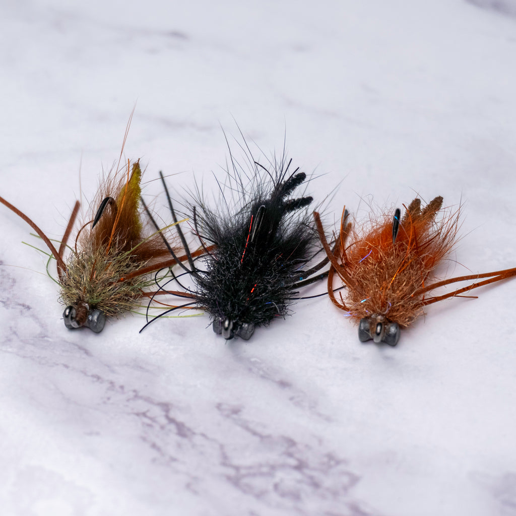 Three Bourbon Crab fly variations from the limited Summer Collection featuring muddy olive, black, and tan colorways designed for spooky redfish and black drum in skinny water.