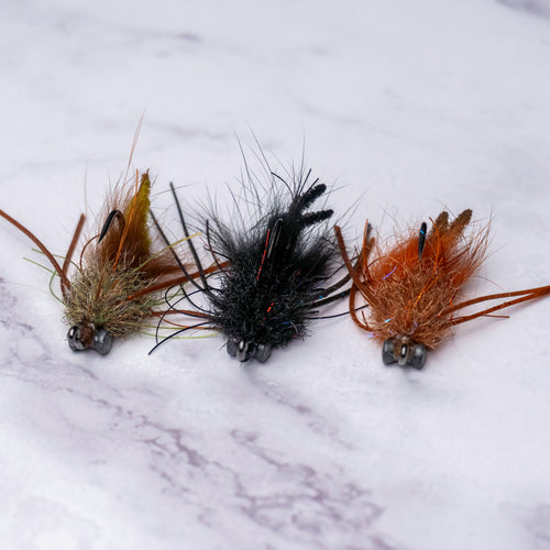 Three Bourbon Crab fly variations from the limited Summer Collection featuring muddy olive, black, and tan colorways designed for spooky redfish and black drum in skinny water.