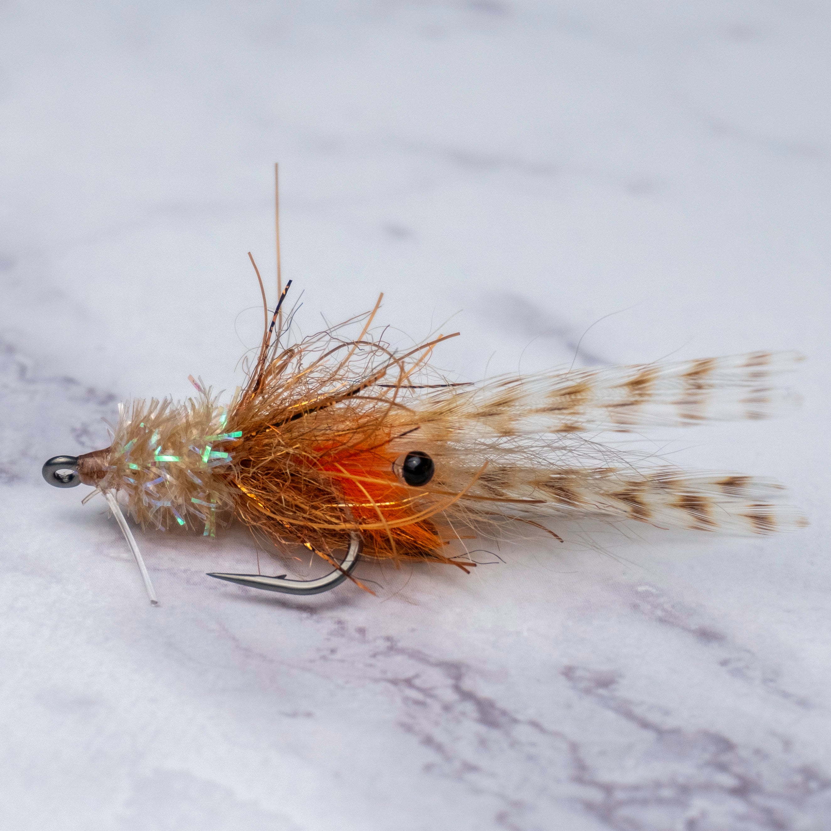 Hand-tied Bull Shrimp fly pattern from the Summer Collection with natural tan fibers, orange accents, weedguard, and spotted tail for quiet presentations to tailing fish in grass flats.