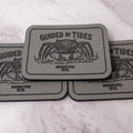 Gray 2.8 x 4 inch Southern Style Fly Co. peel-and-stick foam fly pad featuring the Guided by Tides mangrove crab logo, designed for mounting on fly boxes, coolers, and boat consoles.