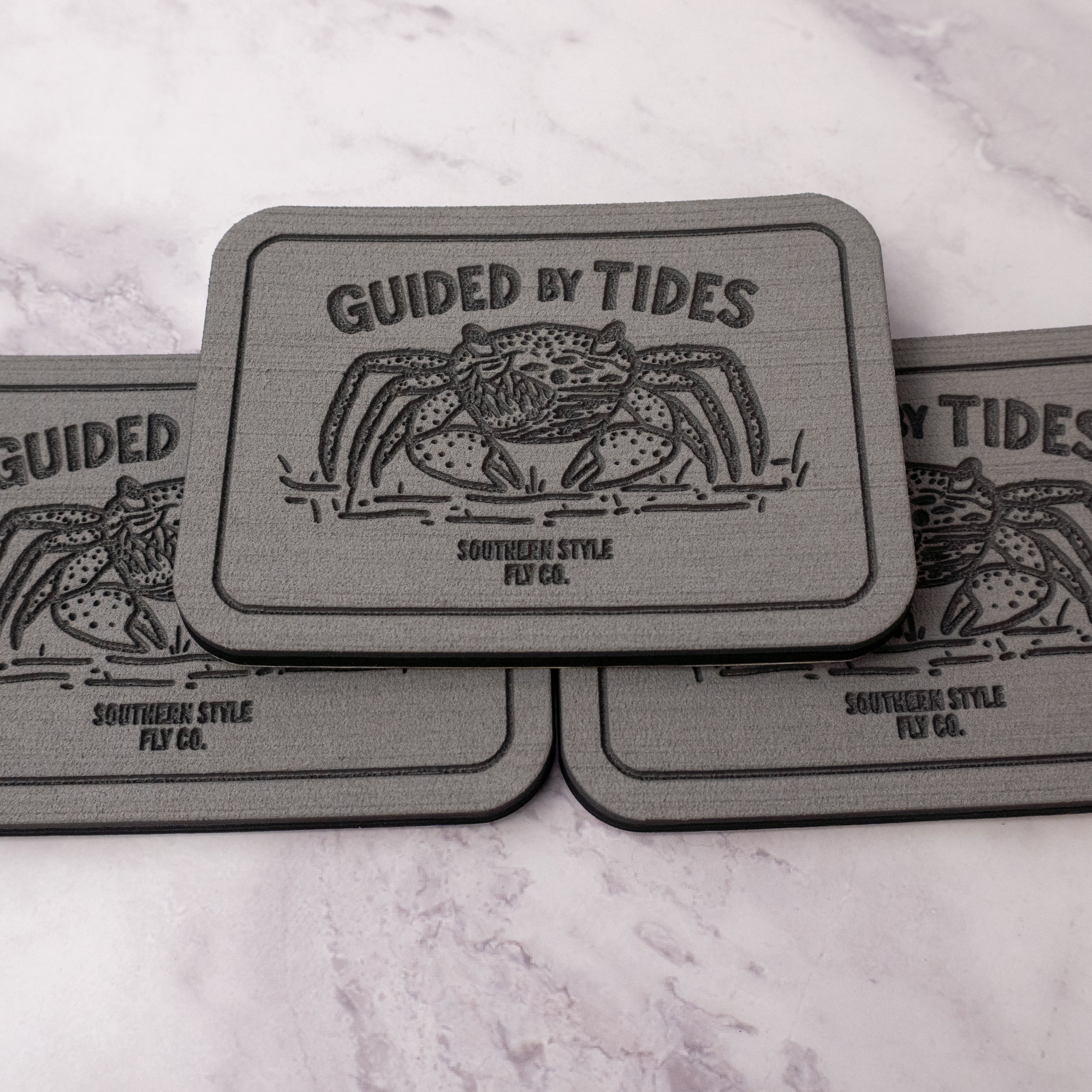 Gray 2.8 x 4 inch Southern Style Fly Co. peel-and-stick foam fly pad featuring the Guided by Tides mangrove crab logo, designed for mounting on fly boxes, coolers, and boat consoles.