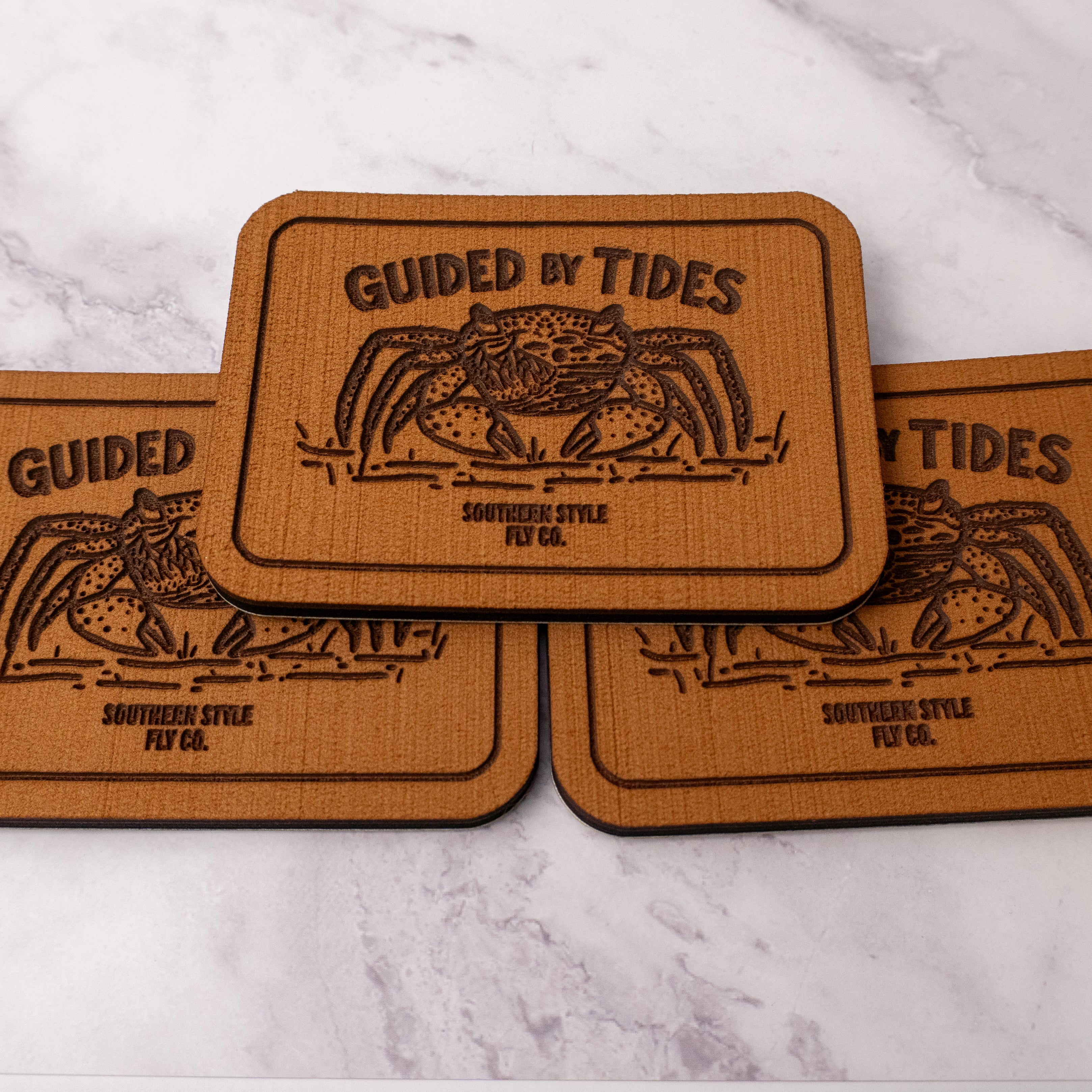 Tan 2.8 x 4 inch Southern Style Fly Co. peel-and-stick foam fly pad with the Guided by Tides mangrove crab logo and adhesive backing for organizing flies on the water.