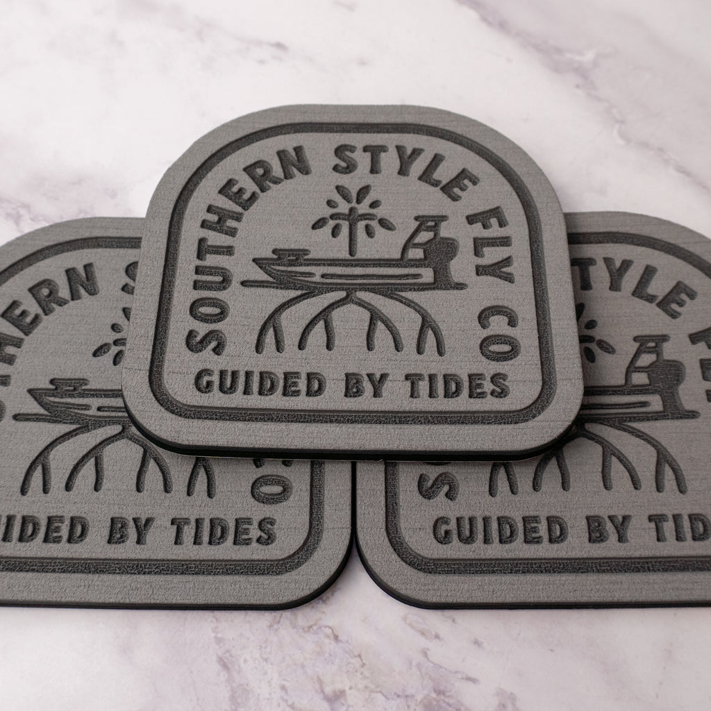 Gray 3.7 x 4 inch Southern Style Fly Co. Guided By Tides Skiff logo foam fly pad with adhesive backing for organizing saltwater and freshwater flies on boats, coolers, and fly boxes.