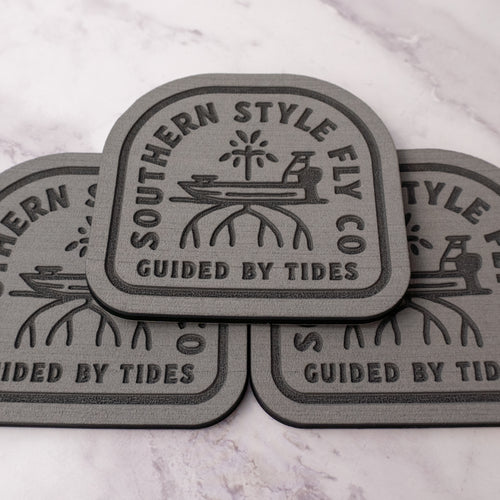 Gray 3.7 x 4 inch Southern Style Fly Co. Guided By Tides Skiff logo foam fly pad with adhesive backing for organizing saltwater and freshwater flies on boats, coolers, and fly boxes.