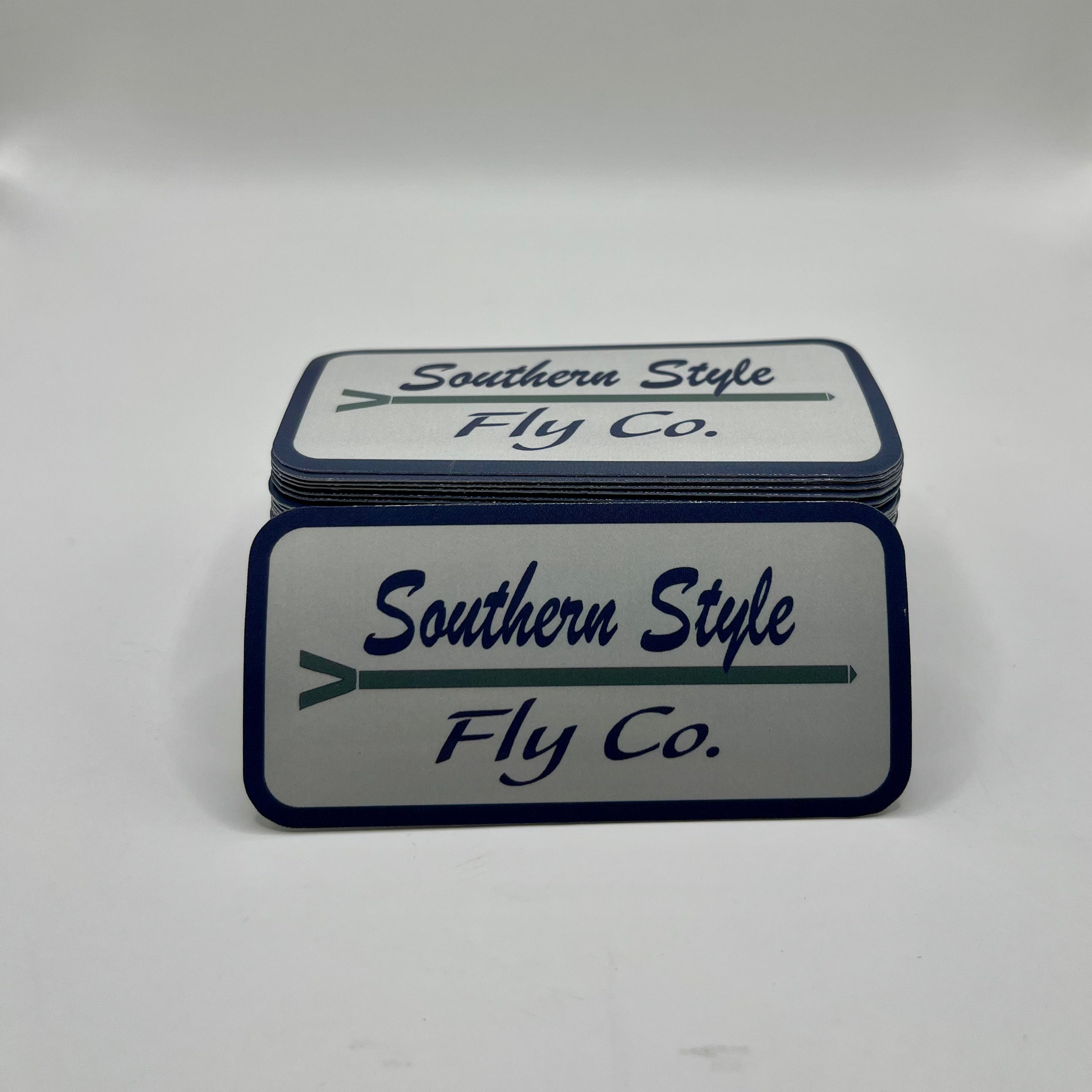 Macro close-up of a Southern Style Fly Co. square sticker with a white background, blue logo, and the text “Guided by Tides.”