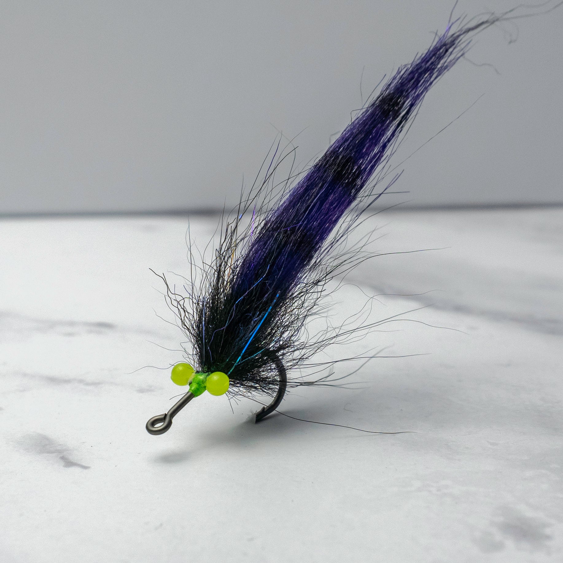 Black and purple Sawgrass Shrimp fly pattern with fluorescent eyes tied for low-light snook and tarpon fishing applications.
