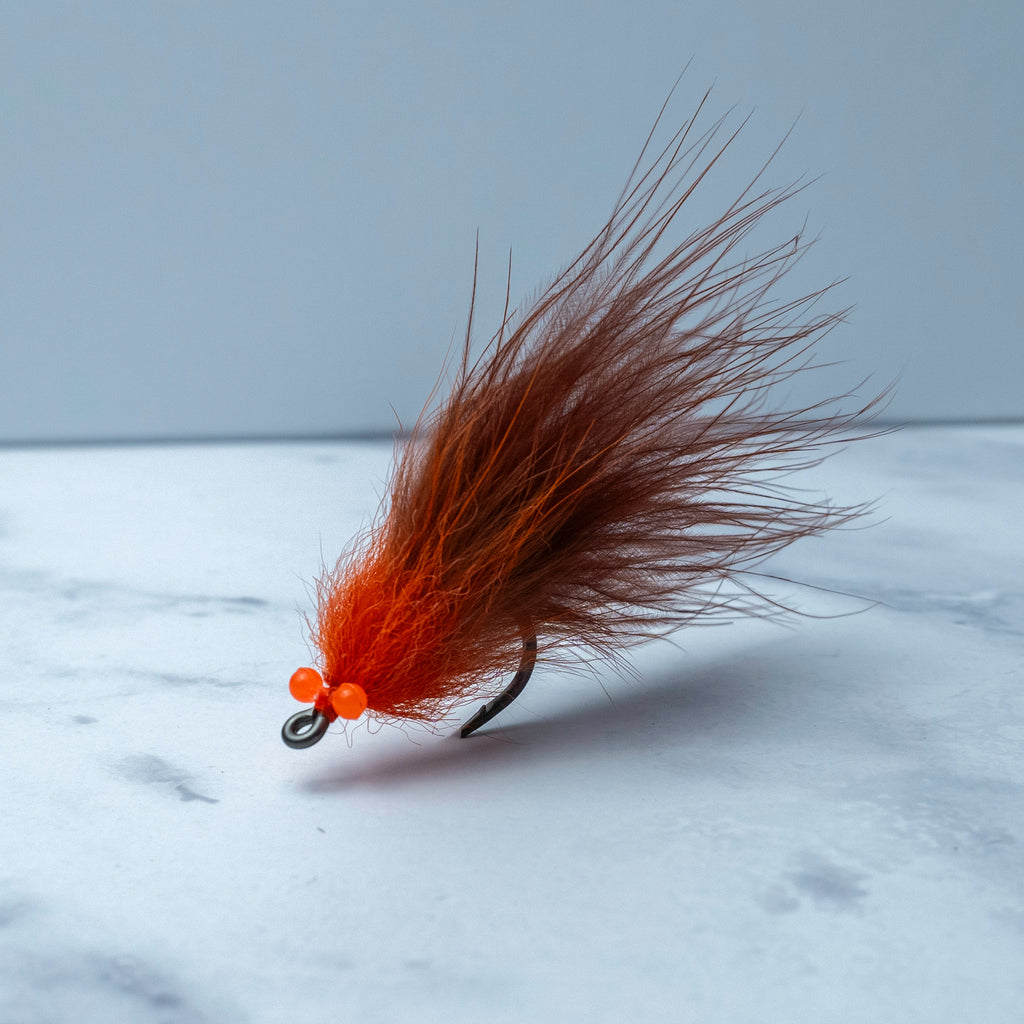 Orange and brown South Bounder tarpon fly tied on a Size 1/0 Mustad Big Game Hook with flowing natural materials and bright orange head accents.