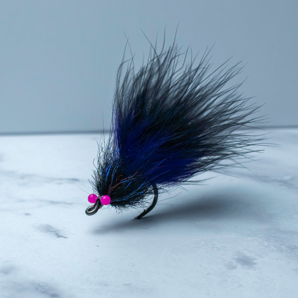 Black and purple South Bounder tarpon fly with subtle flash accents tied on a Size 1/0 Mustad Big Game Hook for low-light and dirty water conditions.