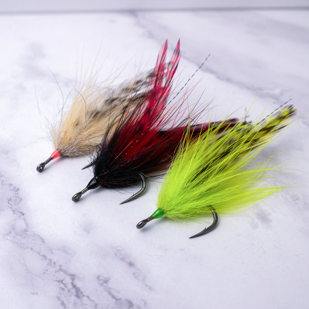 Three Southern Roach tarpon flies in natural, black and red, and chartreuse color patterns tied on saltwater hooks for fly fishing.
