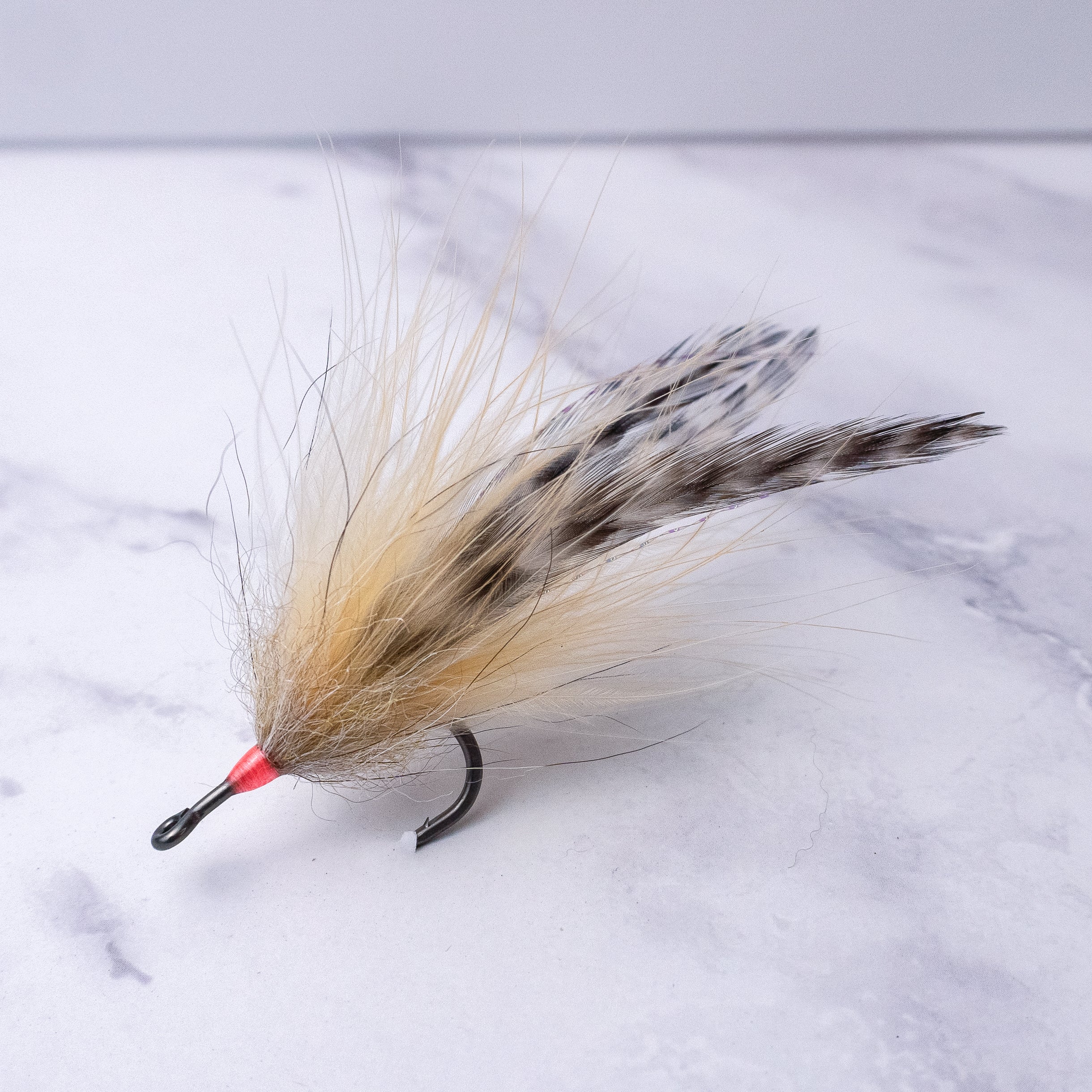 Natural-colored Southern Roach tarpon fly featuring tan bucktail, flowing hair, and barred saddle hackles on a saltwater fly hook.
