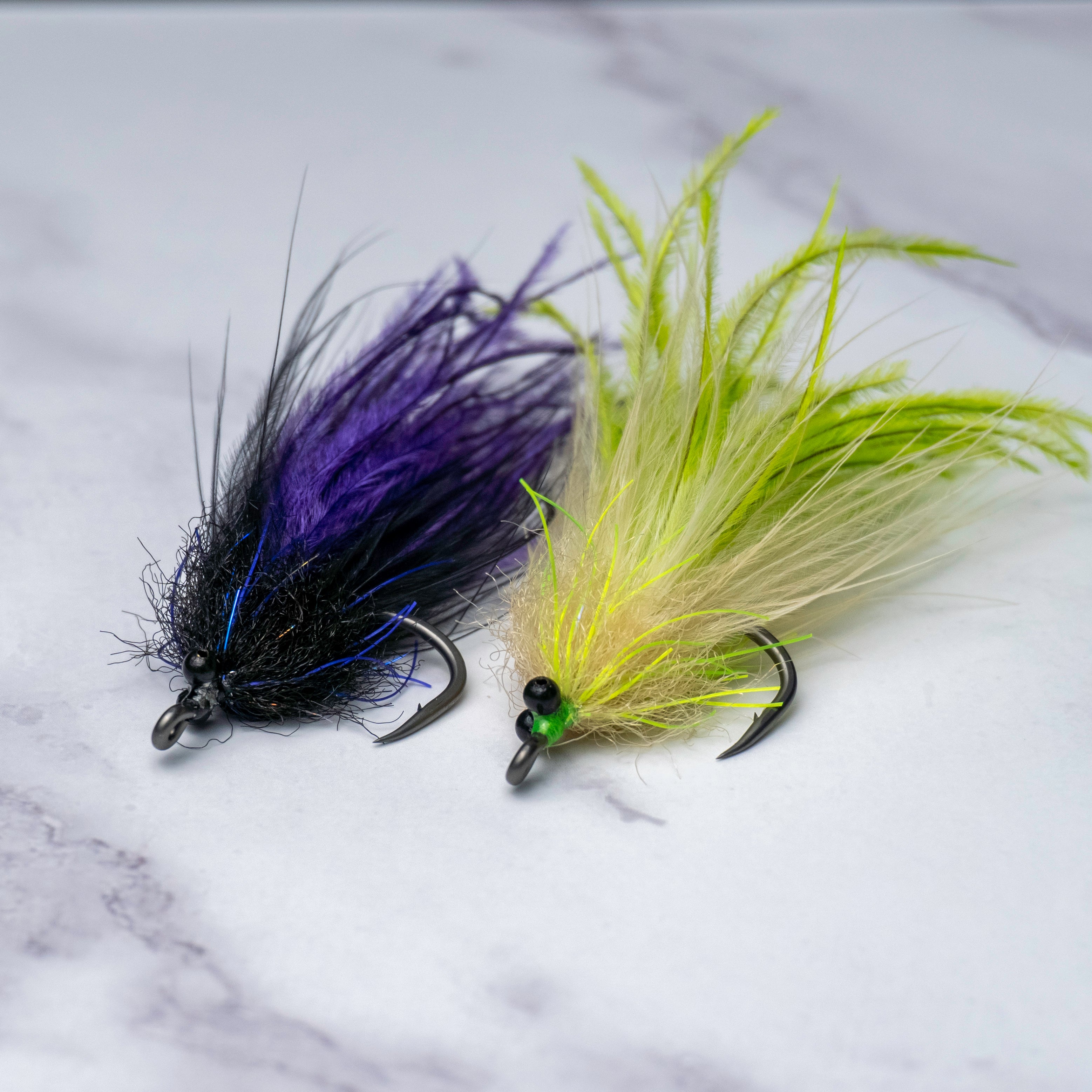Two Tickler tarpon flies in chartreuse tan and black purple color variations, featuring beach chain eyes and suspended flowing profiles built for glades fish, laid-up tarpon, and coastal summer migration fish.